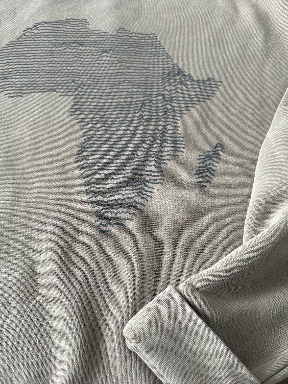 Detail of cement color sweatshirt with a dark gray topographical map of Africa design