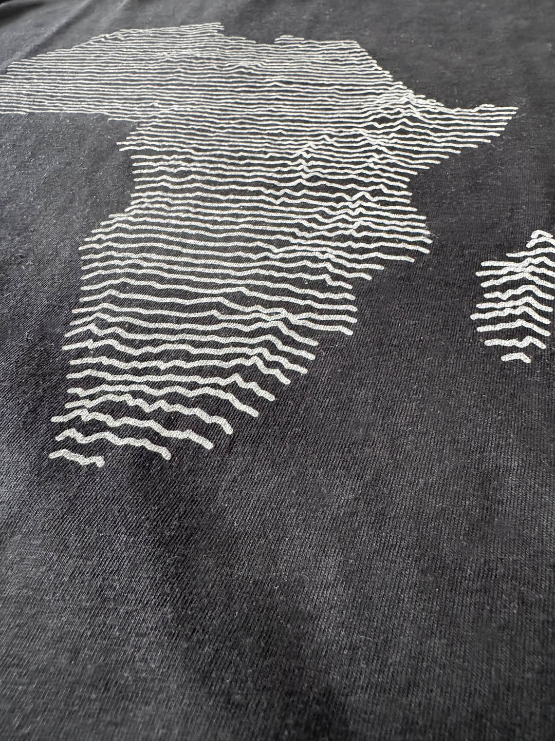 Detail of black t-shirt with medium gray topographical map of Africa design
