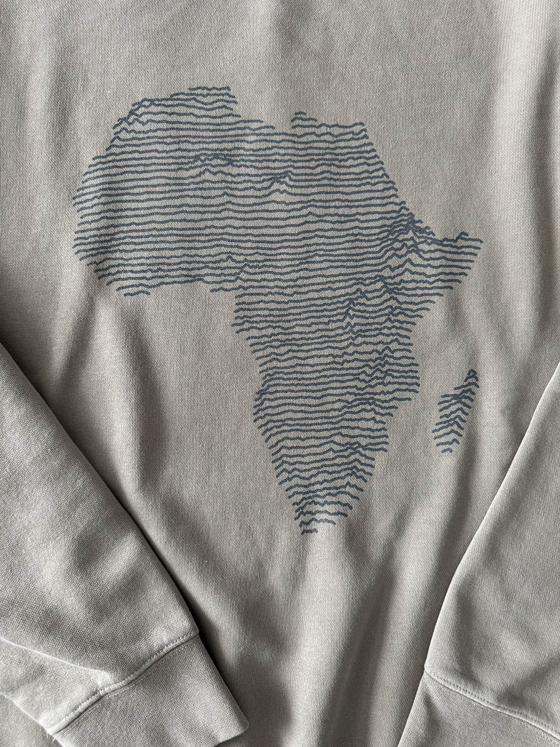 Detail of cement color sweatshirt with a dark gray topographical map of Africa design